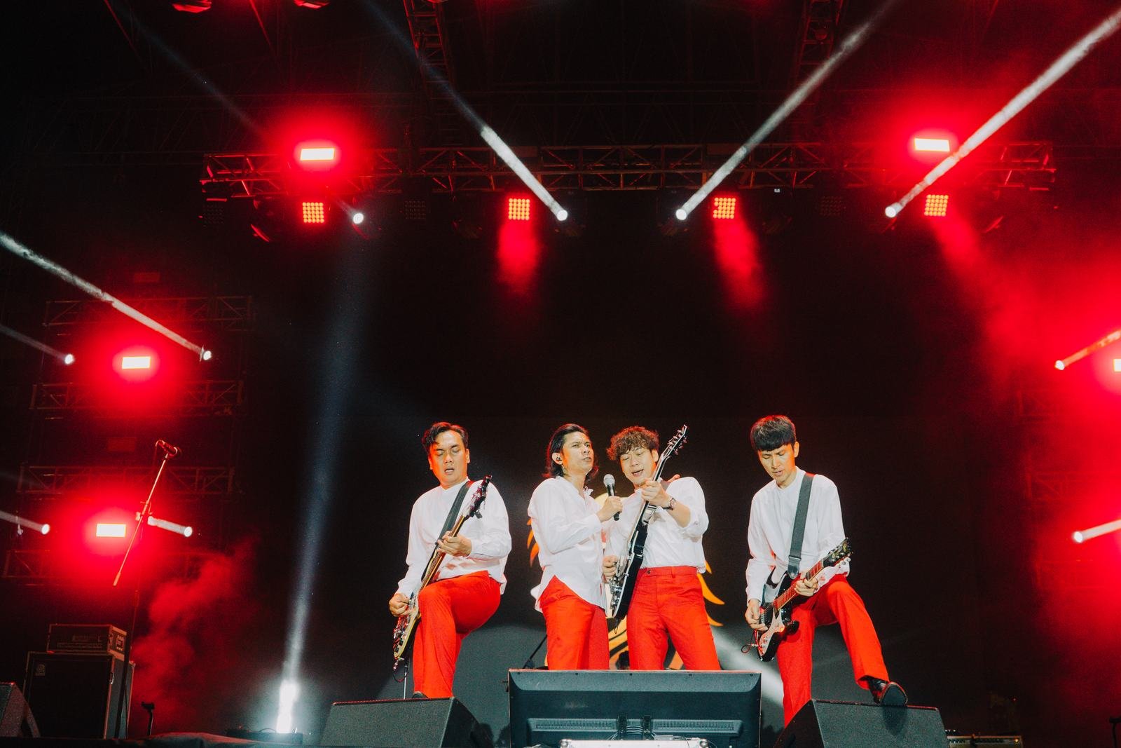 Band tampil dengan lampu merah di panggung outdoor